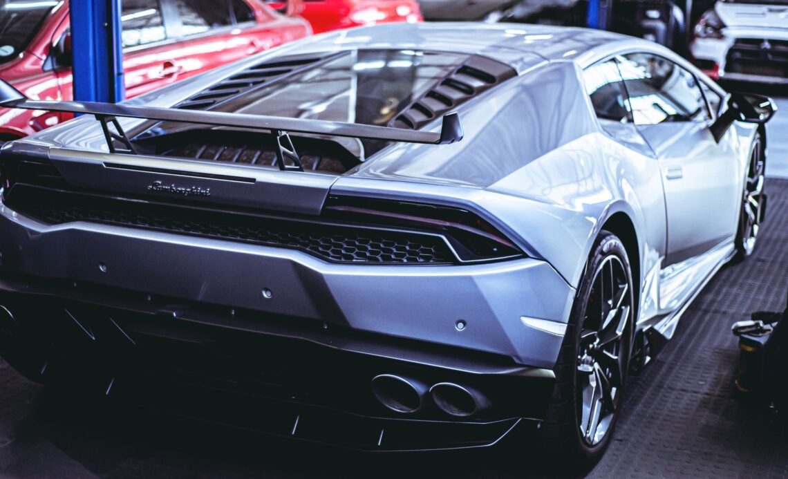Silverfärgad Lamborghini med stor bakvinge i en bilverkstad