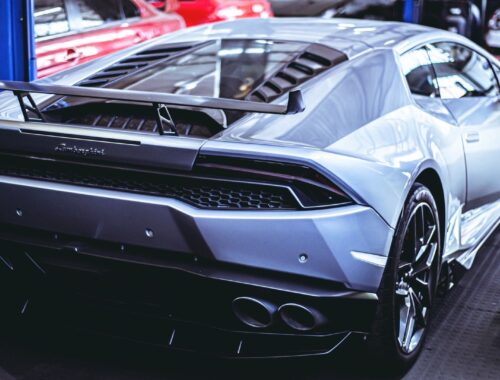 Silverfärgad Lamborghini med stor bakvinge i en bilverkstad